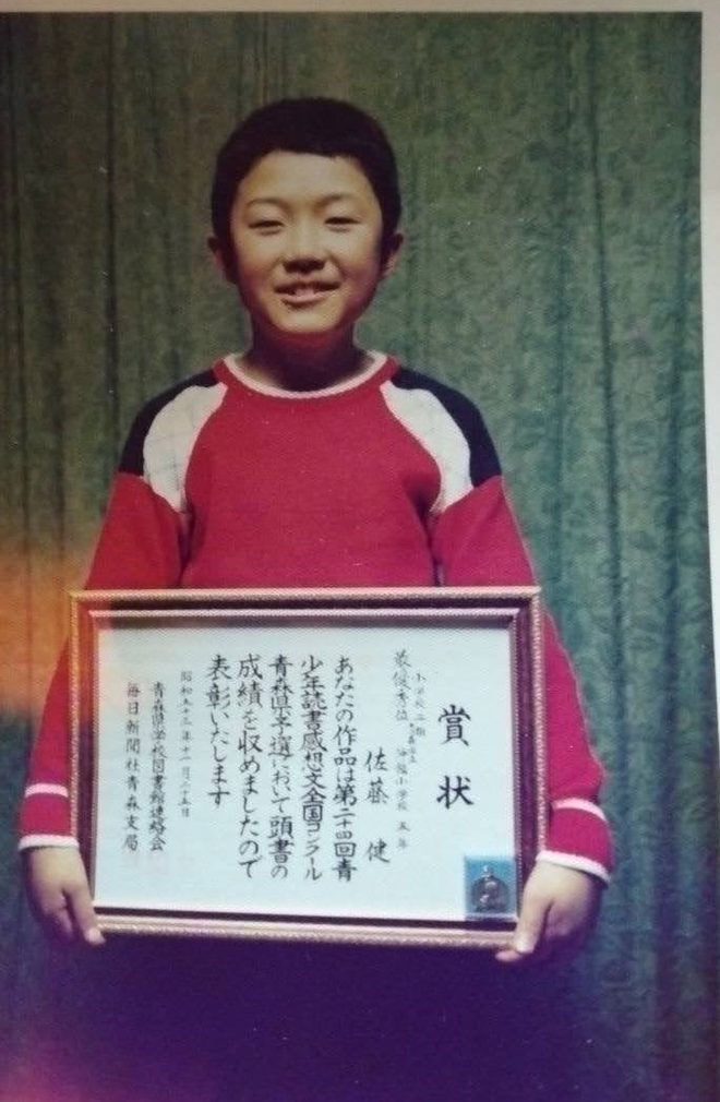 A boy in Aomori holding a framed certificate
